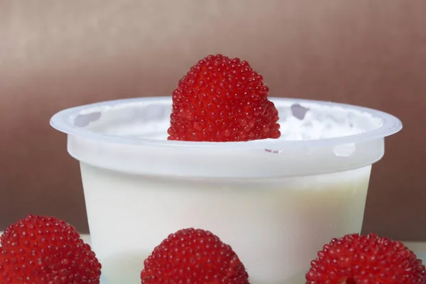 Crema agria de gelatina en un frasco, decorado con frambuesas. Sobre un fondo marrón . — Foto de Stock