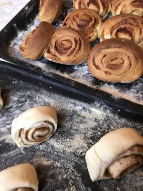 Evde tarçın ile buns hazırlanması. Tablo iki fırın yaprak vardır. Bir hazır buns, ham ile diğer ile.