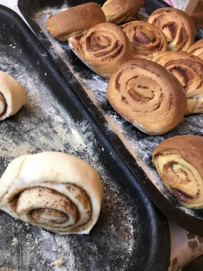 Evde tarçın ile buns hazırlanması. Tablo iki fırın yaprak vardır. Bir hazır buns, ham ile diğer ile.