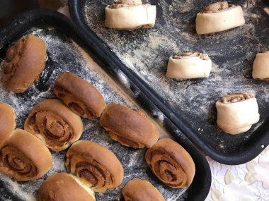 Evde tarçın ile buns hazırlanması. Tablo iki fırın yaprak vardır. Bir hazır buns, ham ile diğer ile.