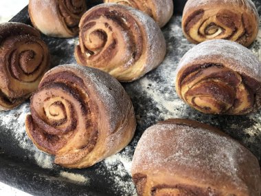 Evde tarçın ile buns hazırlanması. Hazır kırmızı buns bir tepsi üzerinde yalan.
