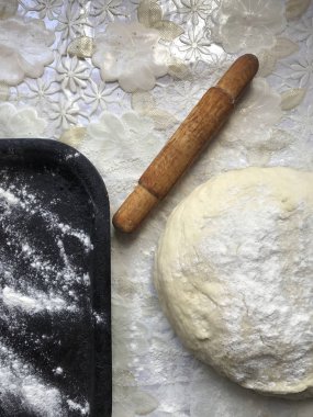 Evde tarçın ile buns hazırlanması. Tepsiyi un serpilir, hamur ve ahşap bir haddeleme pin masanın üstüne yalan. Tarçın şeker bir kupa ile.