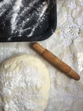 Evde tarçın ile buns hazırlanması. Tepsiyi un serpilir, hamur ve ahşap bir haddeleme pin masanın üstüne yalan. Tarçın şeker bir kupa ile.