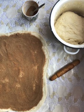 Evde tarçın ile buns hazırlanması. Tepsiyi un serpilir, hamur ve ahşap bir haddeleme pin masanın üstüne yalan. Hamur tarçın ve suga ile serpilir