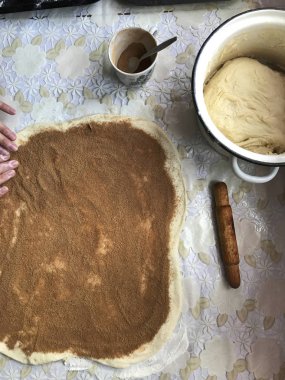 Evde tarçın ile buns hazırlanması. Tepsiyi un serpilir, hamur ve ahşap bir haddeleme pin masanın üstüne yalan. Hamur tarçın ve suga ile serpilir