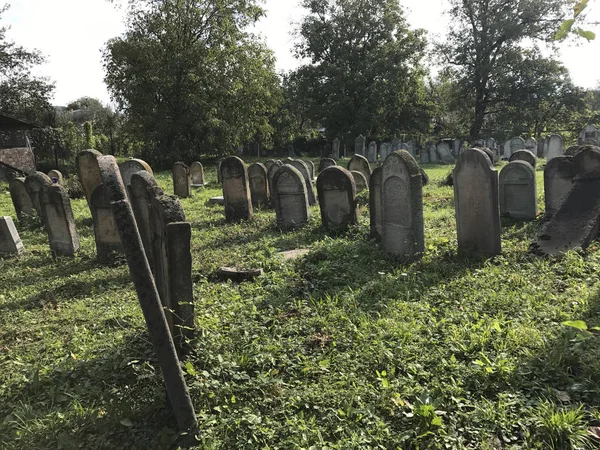 TERESVA, UCRÂNIA, 18 de setembro de 2017; Um antigo cemitério judeu. Pedras quebradas estão entre a grama verde. Neles - inscrições em hebraico . — Fotografia de Stock