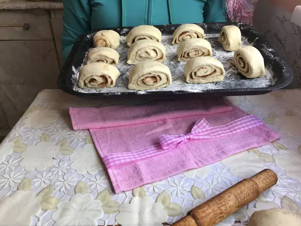 Подготовка булочек с корицей дома. Женщина держит поднос для выпечки с булочками . — стоковое фото