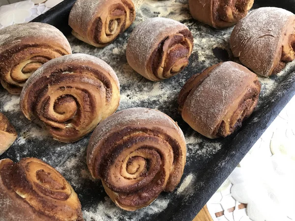 Evde tarçın ile buns hazırlanması. Hazır kırmızı buns bir tepsi üzerinde yalan.