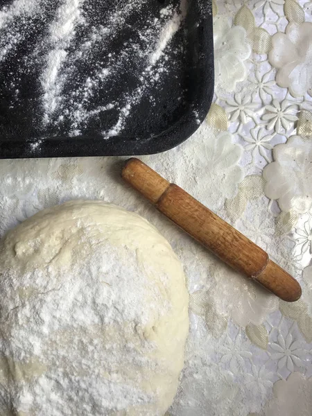 Evde tarçın ile buns hazırlanması. Tepsiyi un serpilir, hamur ve ahşap bir haddeleme pin masanın üstüne yalan. Tarçın şeker bir kupa ile.