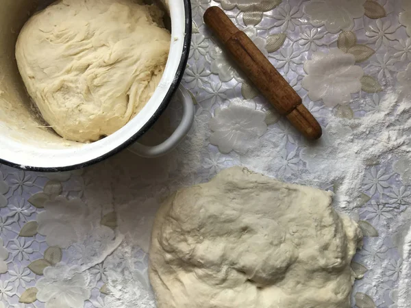 Подготовка булочек с корицей дома. Поднос посыпают мукой, тестом и деревянной скалкой, лежащей на столе . — стоковое фото