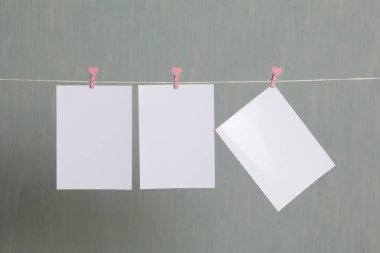 Fotoğrafik baskılar sonra gelişmekte olan bir kablosunun üzerine ve kuru sıkı. İçerik eklemek için bir yer vardır. Giyim mandal farklı pozisyonlarda kablosuyla bağlı. Bir gri-yeşil arka plan üzerinde.