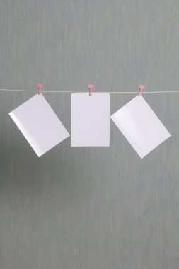 Fotoğrafik baskılar sonra gelişmekte olan bir kablosunun üzerine ve kuru sıkı. İçerik eklemek için bir yer vardır. Giyim mandal farklı pozisyonlarda kablosuyla bağlı. Bir gri-yeşil arka plan üzerinde.