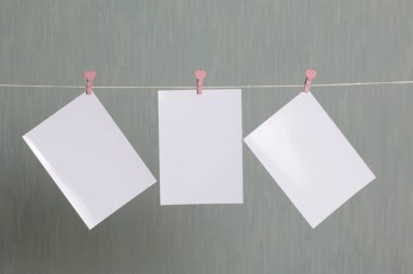 Fotoğrafik baskılar sonra gelişmekte olan bir kablosunun üzerine ve kuru sıkı. İçerik eklemek için bir yer vardır. Giyim mandal farklı pozisyonlarda kablosuyla bağlı. Bir gri-yeşil arka plan üzerinde.