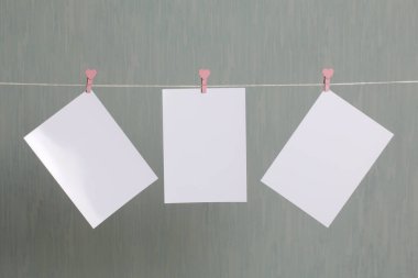 Fotoğrafik baskılar sonra gelişmekte olan bir kablosunun üzerine ve kuru sıkı. İçerik eklemek için bir yer vardır. Giyim mandal farklı pozisyonlarda kablosuyla bağlı. Bir gri-yeşil arka plan üzerinde.