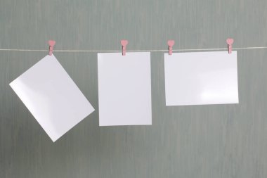 Fotoğrafik baskılar sonra gelişmekte olan bir kablosunun üzerine ve kuru sıkı. İçerik eklemek için bir yer vardır. Giyim mandal farklı pozisyonlarda kablosuyla bağlı. Bir gri-yeşil arka plan üzerinde.