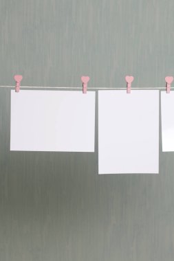 Fotoğrafik baskılar sonra gelişmekte olan bir kablosunun üzerine ve kuru sıkı. İçerik eklemek için bir yer vardır. Giyim mandal farklı pozisyonlarda kablosuyla bağlı. Bir gri-yeşil arka plan üzerinde.