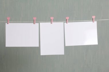 Fotoğrafik baskılar sonra gelişmekte olan bir kablosunun üzerine ve kuru sıkı. İçerik eklemek için bir yer vardır. Giyim mandal farklı pozisyonlarda kablosuyla bağlı. Bir gri-yeşil arka plan üzerinde.