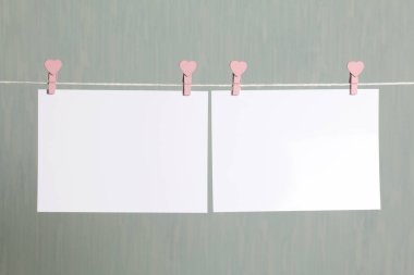 Fotoğrafik baskılar sonra gelişmekte olan bir kablosunun üzerine ve kuru sıkı. İçerik eklemek için bir yer vardır. Giyim mandal farklı pozisyonlarda kablosuyla bağlı. Bir gri-yeşil arka plan üzerinde.