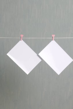 Fotoğrafik baskılar sonra gelişmekte olan bir kablosunun üzerine ve kuru sıkı. İçerik eklemek için bir yer vardır. Giyim mandal farklı pozisyonlarda kablosuyla bağlı. Bir gri-yeşil arka plan üzerinde.