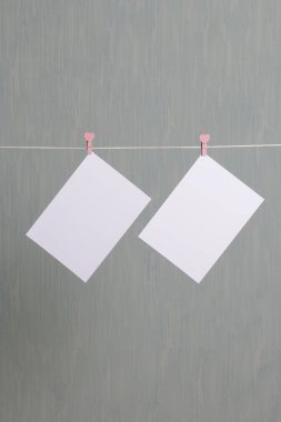 Fotoğrafik baskılar sonra gelişmekte olan bir kablosunun üzerine ve kuru sıkı. İçerik eklemek için bir yer vardır. Giyim mandal farklı pozisyonlarda kablosuyla bağlı. Bir gri-yeşil arka plan üzerinde.