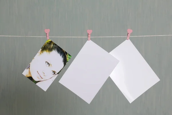 Fotografische afdrukken hangen na het ontwikkelen van op een koord en droog. Er is een plek om uw inhoud invoegen. Gekoppeld aan het koord met wasknijpers in verschillende posities. Op een grijs-groene achtergrond. — Stockfoto