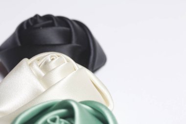 Ev yapımı gül siyah, beyaz ve zümrüt saten. Beyaz bir arka plan üzerinde.