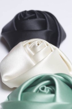 Ev yapımı gül siyah, beyaz ve zümrüt saten. Beyaz bir arka plan üzerinde.