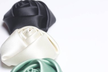 Ev yapımı gül siyah, beyaz ve zümrüt saten. Beyaz bir arka plan üzerinde.