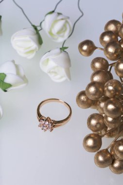 Kutlamalar için süsler. Altın yüzük taşlar ve yapay çiçekler buket. Beyaz bir arka plan üzerinde.