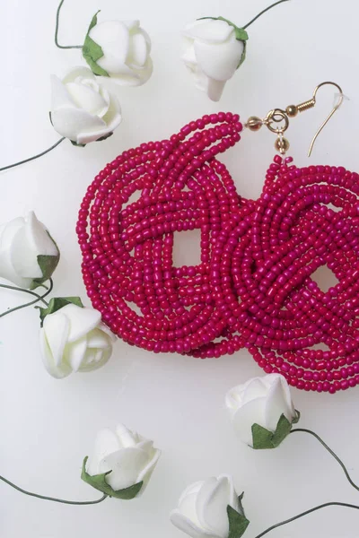 Female earrings of coral color. Hand made of beads. Artificial roses are beige for decoration. On a white background. — Stock Photo, Image