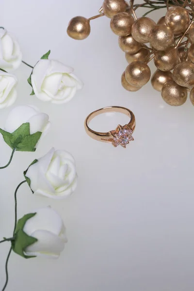 Ornamenten voor feesten. Gouden ring met stenen en boeket van kunstbloemen. Op een witte achtergrond. — Stockfoto