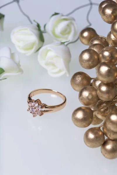 Ornamenten voor feesten. Gouden ring met stenen en boeket van kunstbloemen. Op een witte achtergrond. — Stockfoto