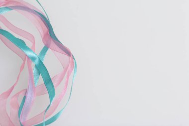 Zümrüt ve pembe rengi saten örgü beyaz bir arka plan üzerinde intertwines.