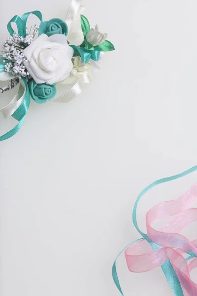 Trança de cetim de esmeralda e cor-de-rosa entrelaça-se em um fundo branco. Perto do casamento boutonniere . — Fotografia de Stock