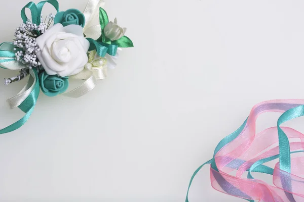 Trança de cetim de esmeralda e cor-de-rosa entrelaça-se em um fundo branco. Perto do casamento boutonniere . — Fotografia de Stock