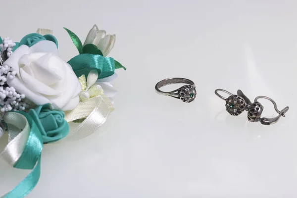 Μπουτονιέρα γαμήλιο δαχτυλίδι και σκουλαρίκια. Σε λευκό φόντο. — Φωτογραφία Αρχείου