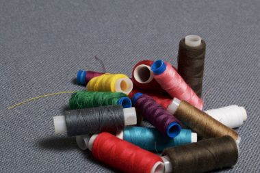 Arka plan iş parçacığı üzerinde gri bir farklı renkteki bobinleri dokuma