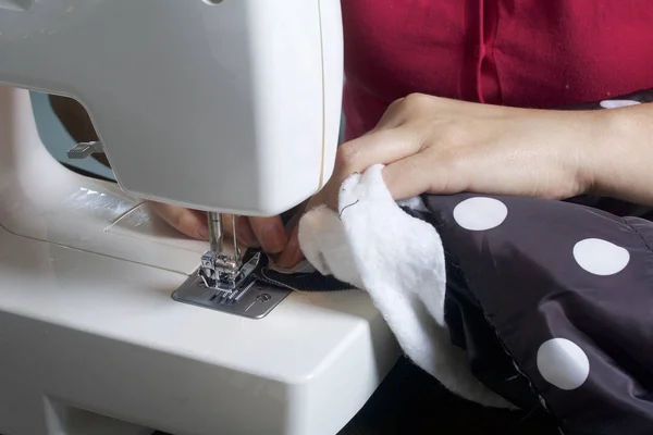 Sy kläder av en enskild entreprenör. En kvinna arbetar på en symaskin. Märlor avskurna delar av produkten. — Stockfoto