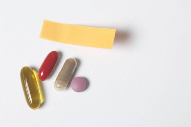 Tablo beyaz yüzey üzerinde farklı renkteki hapları yalan. Sonraki bir hatırlatma ile bir kağıt etiket olduğunu.