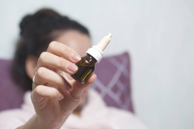 Burun damlası. Kadın onun önünde şişe uzanmış elinde tutan.