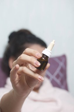 Burun damlası. Kadın onun önünde şişe uzanmış elinde tutan.