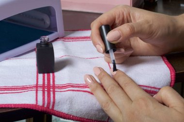 Kaplama ile jel-vernik çivi. Bir kadının tırnaklarını üzerinde bir oje uyguluyor.