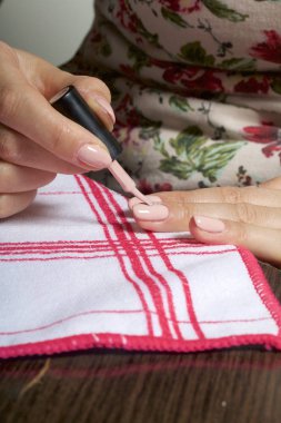 Kaplama ile jel-vernik çivi. Bir kadının tırnaklarını üzerinde bir oje uyguluyor.