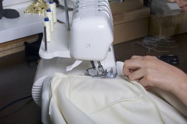 Kadın overlok ürün üzerinde çalışıyor. Beyaz iplik overlok. Kadın overlok pençe içinde klempe bez yönlendirir.