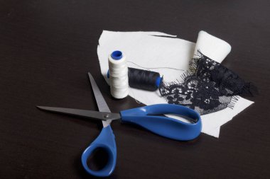 Dikiş ve sos. Karanlık bir yüzeye makas, iplik makaraları ve süsleme kumaş yalan