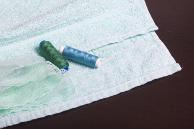 Dekorasyon Tekstil dantel bandı ile. Havlu karanlık bir yüzey üzerinde duruyor. Üzerinde bir dantel kurdele ve iplik bobinleri yatıyor.