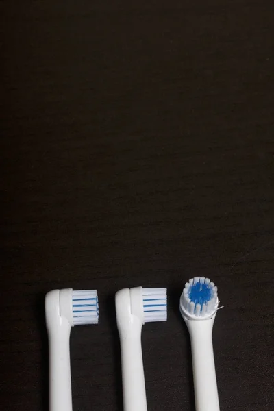Nozzles for electric toothbrush. Lie on a dark surface. — Stock Photo, Image