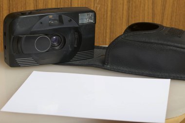 Eski yarı otomatik fotoğraf makinesi. Beyaz bir yüzeye yatıyor. Kamera ve fotoğraf kağıt davadan.