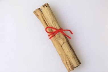Baharat. Beyaz zemin üzerine tarçın. Tarçın ile kırmızı bir iplik bağlanır. Yukarıdan görüntülemek.