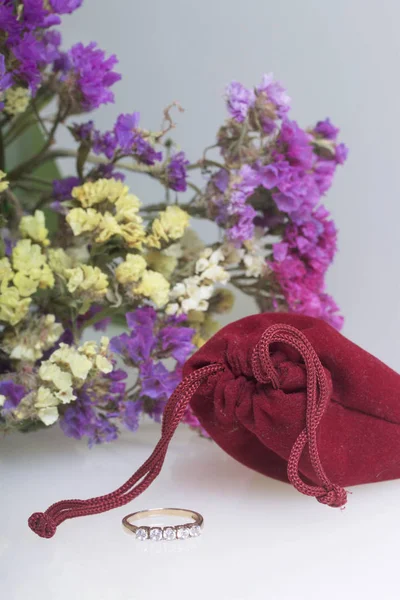 Egy csokor szárított virágok fehér felületen fekszik. Következő, van egy bársony táska ajándékba. A szeretett gyűrű. — Stock Fotó